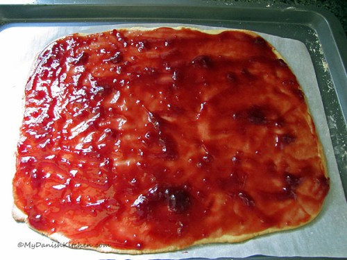 Baked cake topped with raspberry jam, top with second baked cake